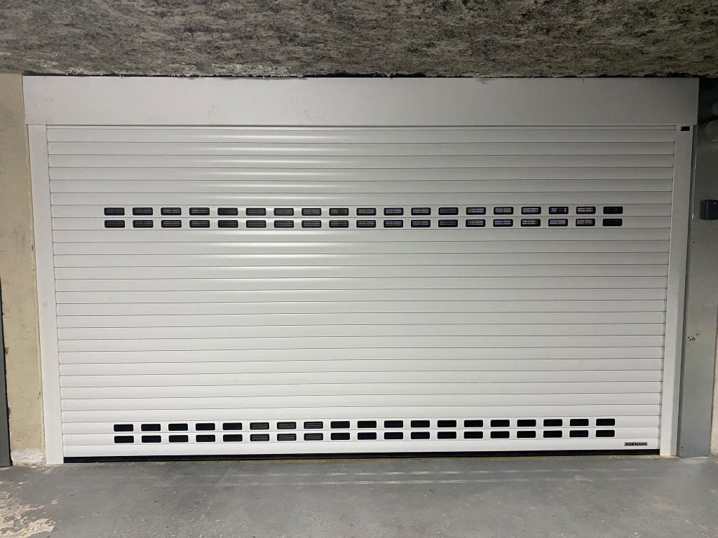 Porte de garage enroulable blanche dans parking à Grasse