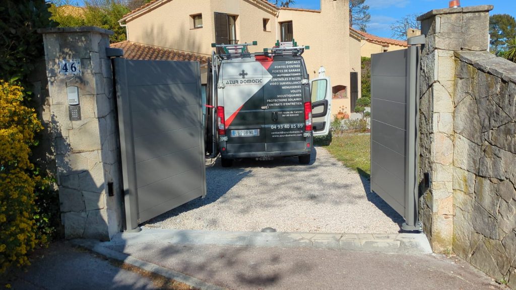 Vue de face du portail battant Tschoeppe bi-vantail aluminium RAL 7016, piliers en pierre naturelle, Valbonne
