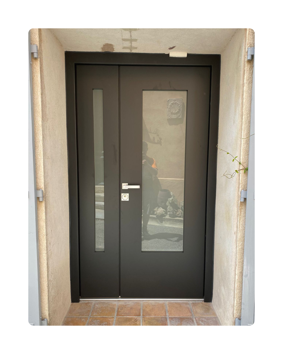 Porte d'entrée double vantaux anthracite avec vitrages intégrés posée dans une maison individuelle