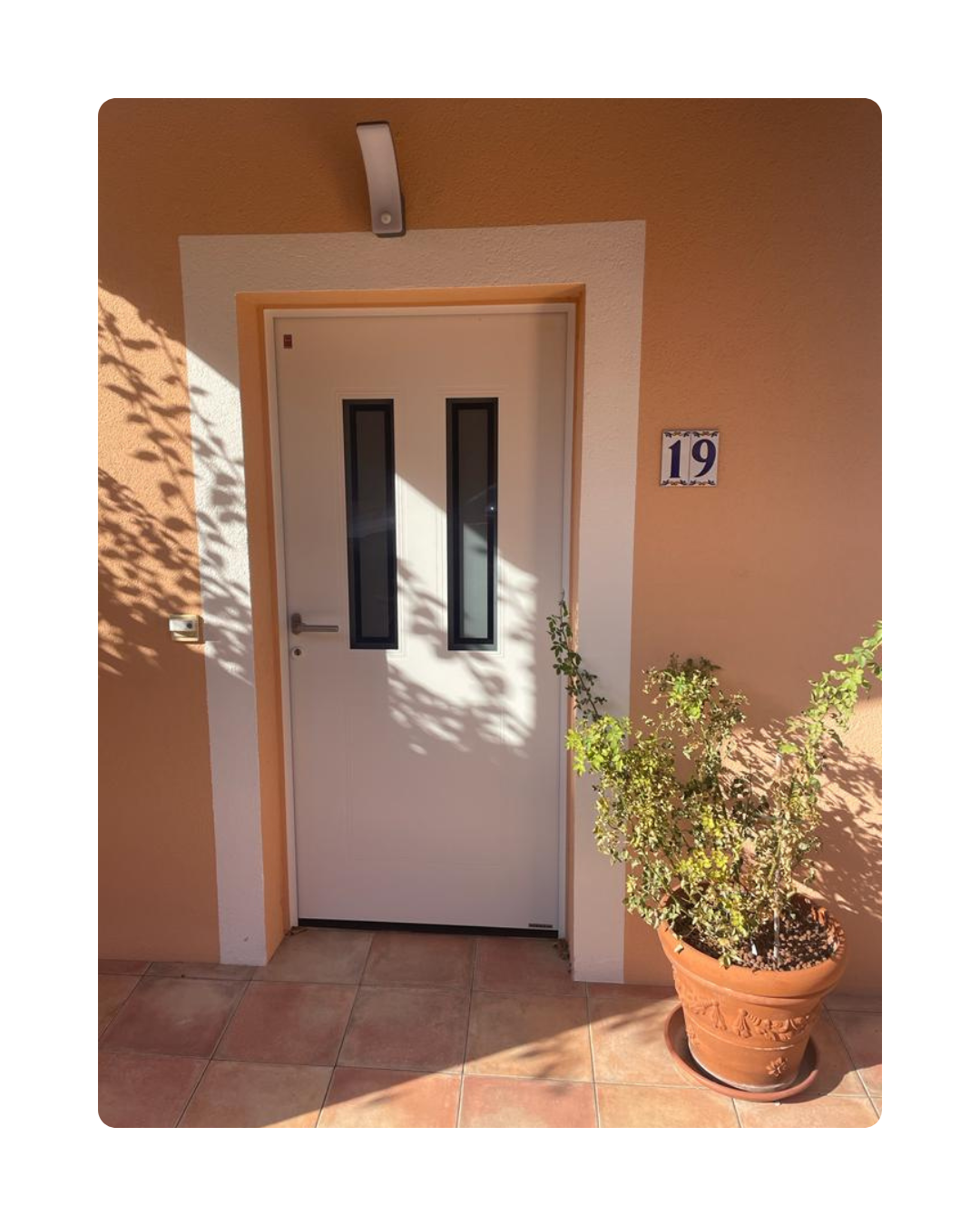 Porte d'entrée Hörmann blanche avec double vitrage installé sur maison individuelle au style méditerranéen