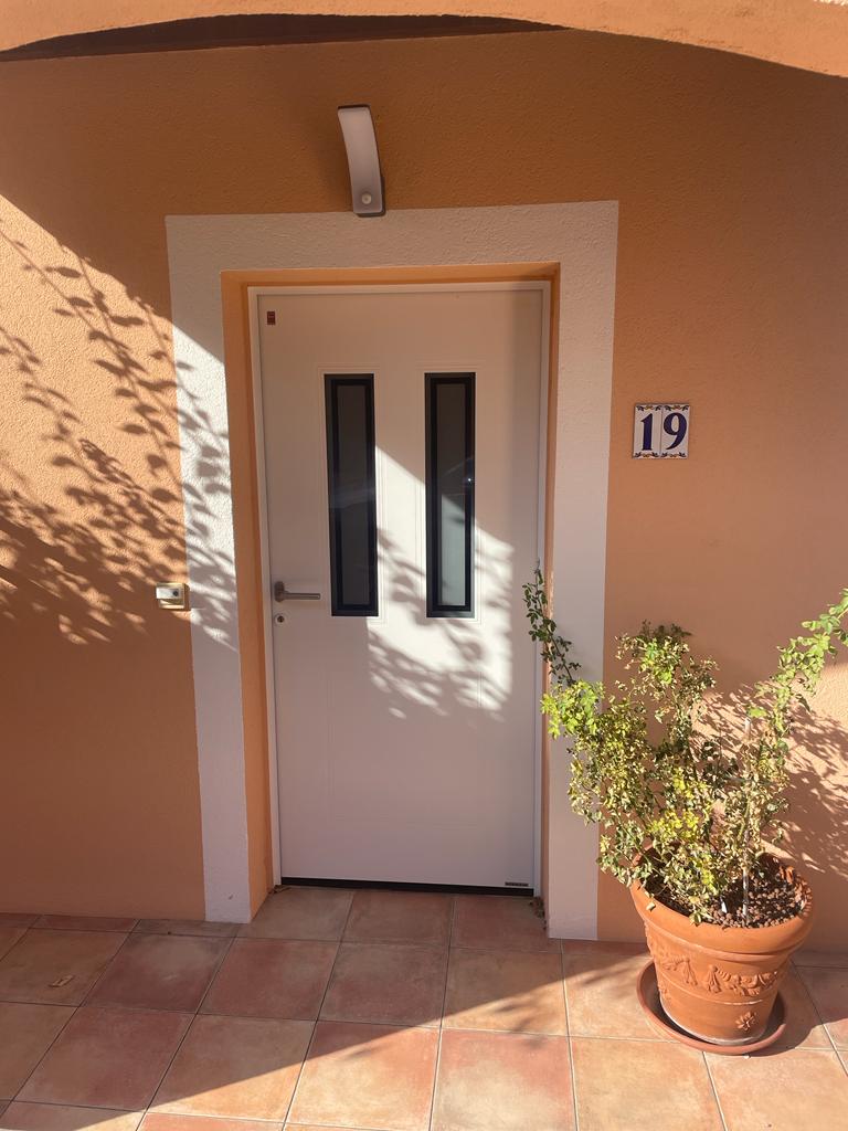 Porte d'entrée Hörmann blanche avec double vitrage installé sur maison individuelle au style méditerranéen