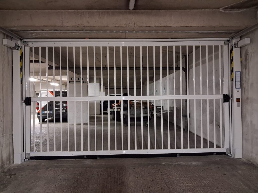 Porte de garage barreaudée Safir fermée vue de l'intérieur du parking souterrain, rampe d'accès en courbe, Cannes boulevard Carnot