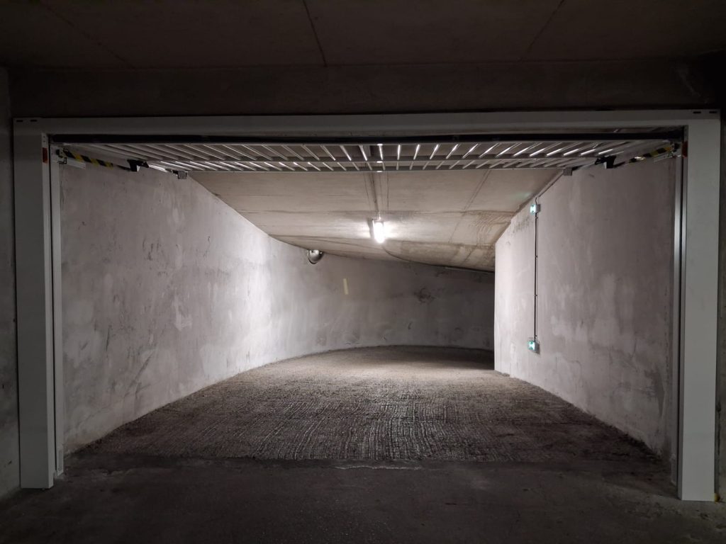 Porte de garage barreaudée Safir ouverte en position haute, vue depuis l'entrée du parking souterrain, Cannes Centre boulevard Carnot