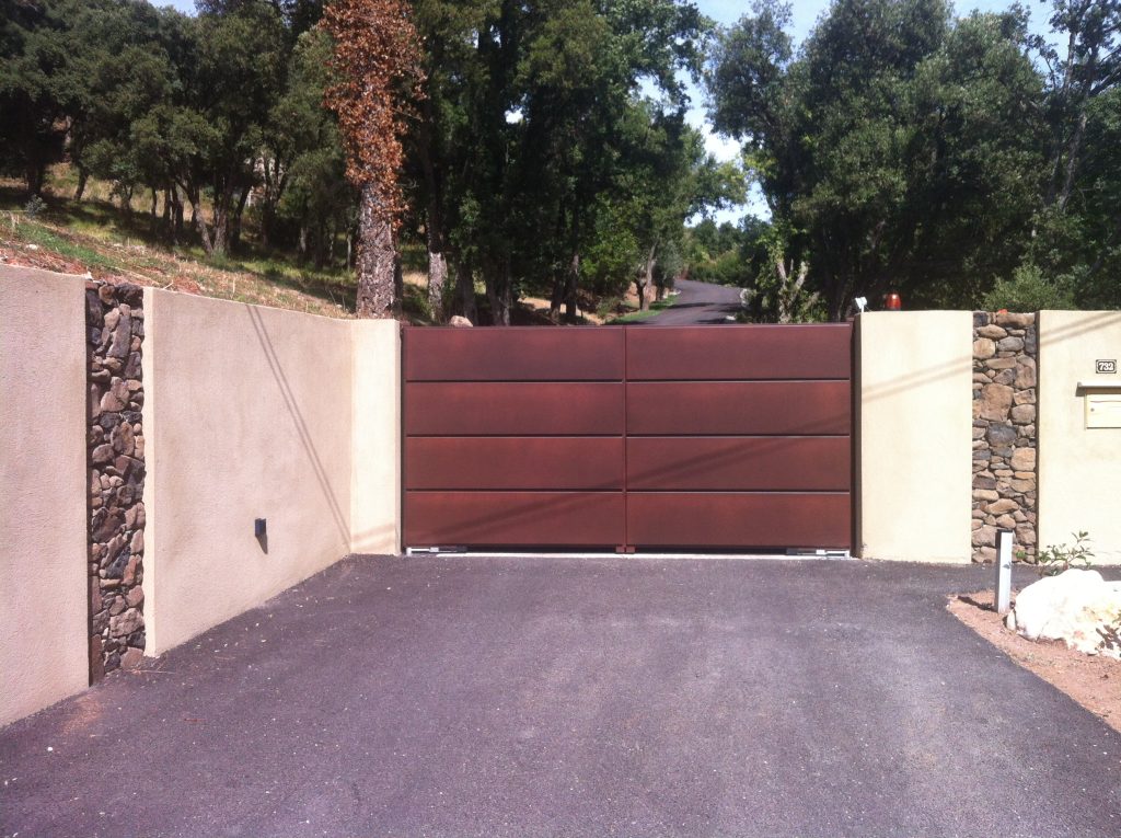 Détail des cassettes horizontales du portail Lucco finition corten devant un massif de lantanas