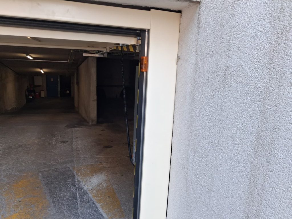 Porte de garage collective SAFIR S424 en position ouverte avec feu orange clignotant et encadrement repeint au Cannet